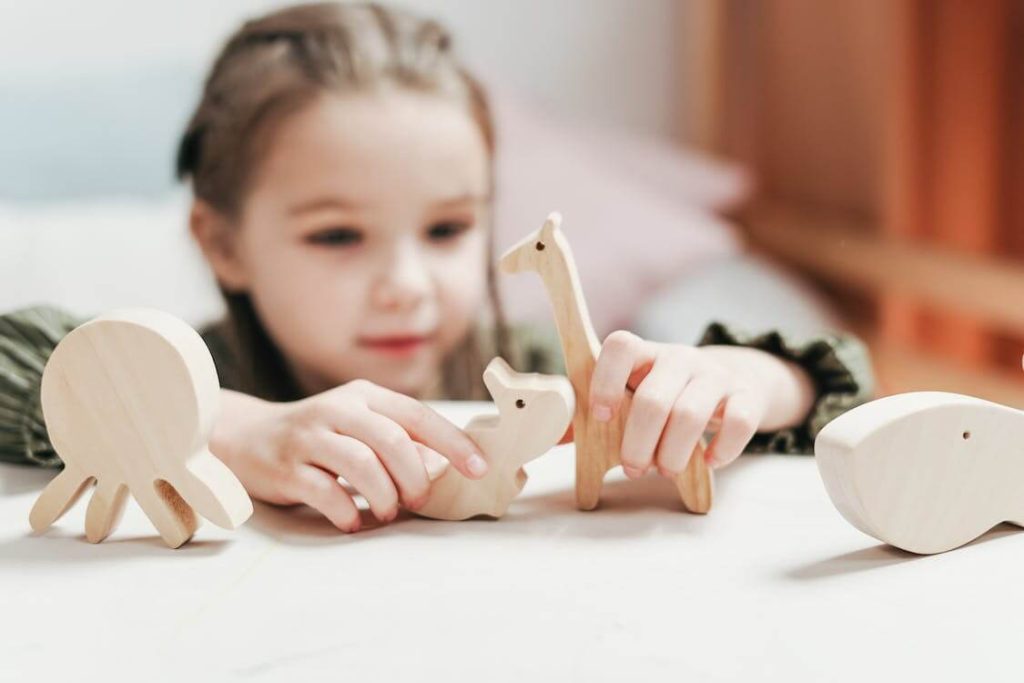 petite fille qui joue avec des animaux en bois